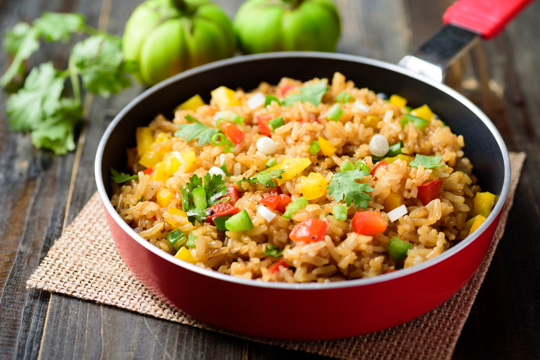 Fried rice with vegetables in cooking pan on wooden background, Asian food